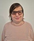 Georgiana Frincu, smiling and wearing a pink-and-white striped sweater, photographed from the front against a light background