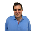 Agustín Aguirre, smiling and wearing a blue polo shirt, photographed from the front against a white background